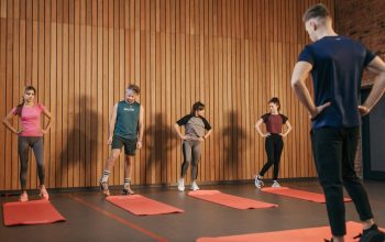 A group exercise class with a personal trainer leading stretching exercises in a gym.